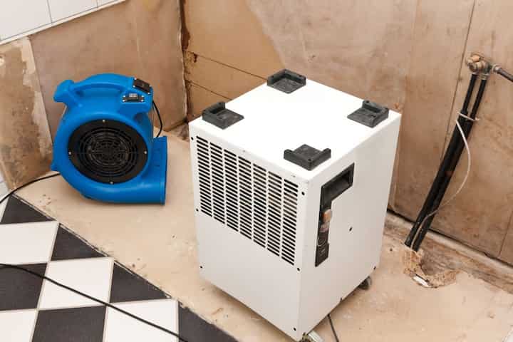 A dehumidifier and air blower are set up in a room to remove moisture during mold remediation in a home in Jackson, TN.